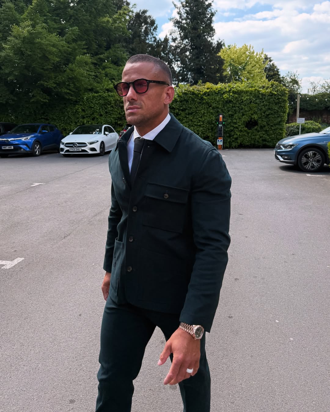 Man in a dark green suit and sunglasses.